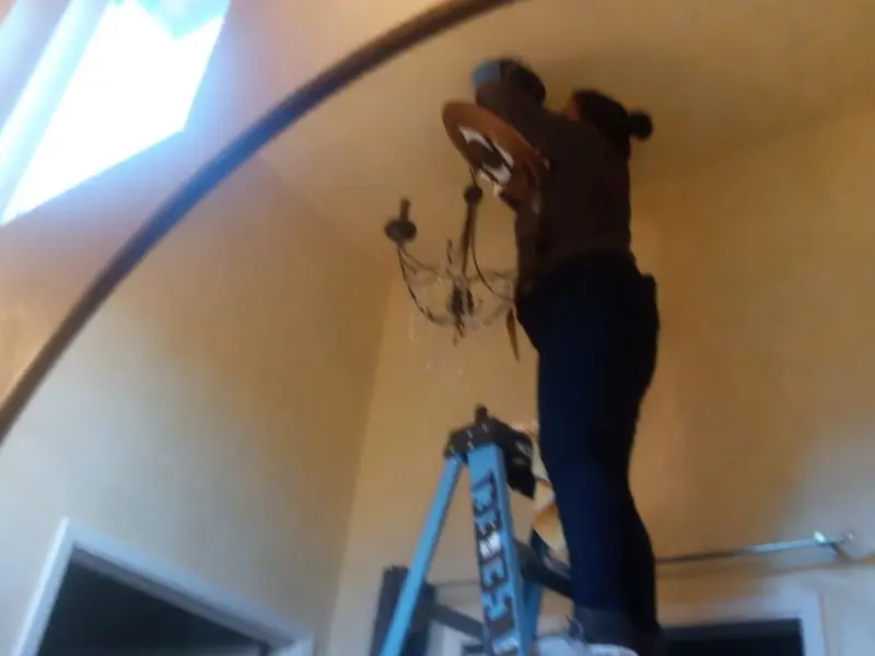 Electrician installing a chandelier in a Houghton residence